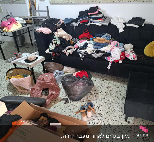בגדים מקופלים ומפוזרים על ספה, קופסאות וארגזים על הרצפה.